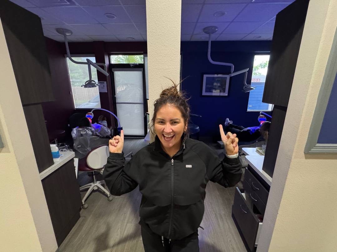 A cheerful Simply Smiles team member celebrating between two treatment chairs at the Sarasota office